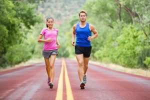 Fitness sport couple running jogging outside on road